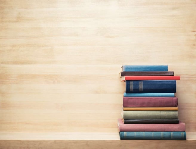 A stack of books on a shelf, real estate investing books concept
