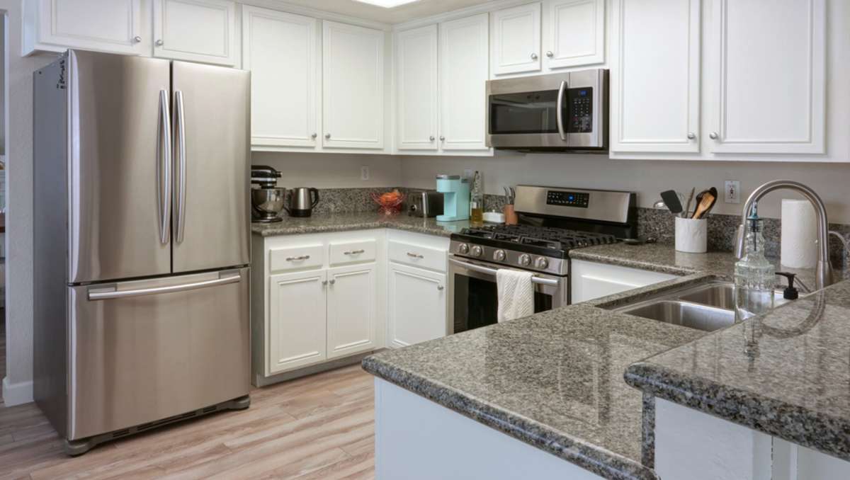 Modern kitchen interior with dark granite counters and stainless steel appliances, single family home in California